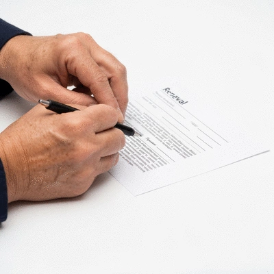 Close-up of hands filling out a renewal form for a license, with a focus on relevant sections and a pen ready to sign